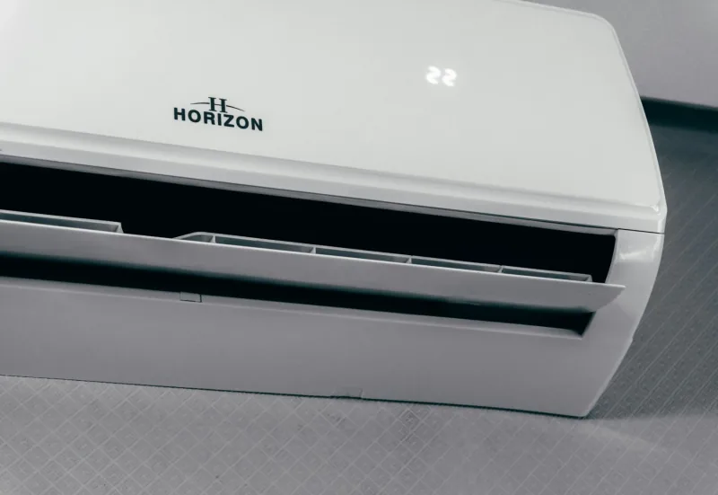 A white wall-mounted indoor air conditioning unit photographed straight on, its supply louvre across the lower edge.